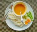 Rice noodle curry with spices and fish Boiled eggs cut in half, long pods, cucumbers, sliced on a white plate Is another popular