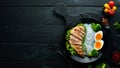 Rice noodles with chicken fillet, egg and broccoli in a black plate on a black background. Top view. Royalty Free Stock Photo