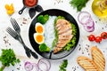 Rice noodles with chicken fillet, egg and broccoli in a black plate on a white wooden background. Top view. Royalty Free Stock Photo