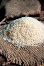 Rice out from small sack isolated on wooden background. Fresh rice in sack bag over wooden textured background. Royalty Free Stock Photo