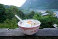 Rice porridge with parboiled egg, minced pork and pepper on wooden table, rice gruel or congee in forest. Royalty Free Stock Photo