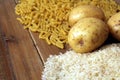 Rice, potatoes and macaroni pasta on a wooden table. Three common carbohydrates which provide energy but can cause obesity