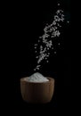Rice pouring into wooden bowl on black background Royalty Free Stock Photo