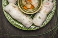 Rice rolls with transparent noodles inside on a green plate with hearbs and vegetable soup on dark wooden rustic background clos Royalty Free Stock Photo