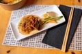 Rice in spicy sauce on sesame pancake, pickled vegetable and fruit on rectangle plate, towel, chopsticks and bowl Royalty Free Stock Photo