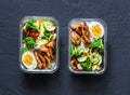 Rice, stewed vegetables, egg, teriyaki chicken - healthy balanced lunch box on a dark background, top view. Home food for office Royalty Free Stock Photo