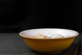 Rice stick noodles in broth with pork and meatballs in bowl on tile table