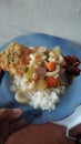 rice with vegetables and fried egg on a blue plate on the table. Indonesian recipe vegetable soup with fried bakwan as a side dish