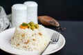 Rice in white plate and carrot and pea grains on it with black wooden background Royalty Free Stock Photo