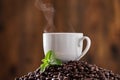 Rich and aromatic. Closeup shot of a mint leaf and a cup on a pile of coffee beans. Royalty Free Stock Photo