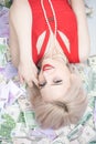 A beautiful blonde woman in a red dress is lying on a lot of money and enjoying life. rich caucasian girl top view