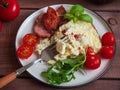 Rich breakfast of scrambled eggs with fried sausage and fresh tomatoes and fresh atromatnye herbs, filmed from close range Royalty Free Stock Photo