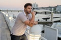 Rich business man dreaming and thinking near the yacht. Handsome man outdoors portrait. Portrait of stylish male model