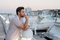 Rich businessman dreaming and thinking near the yacht. Portrait of stylish male model outdoor. Fashion male posing near Royalty Free Stock Photo