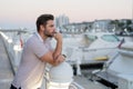 Rich businessman dreaming and thinking near the yacht. Sexy man in casual clothes posing on the street. Successful male