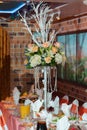 Rich centrepieces made of rose bouquets on tall vases stand