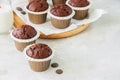 Rich chocolate zucchini muffins on a wooden round plate. White s