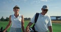 Rich couple talking golf sport outside. Two country club members walk on fairway Royalty Free Stock Photo