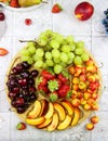 Rich fruit plate filled with fruits and berries. Assortment of black cherry, green grape, yellow cherry, peaches and strawberry on Royalty Free Stock Photo