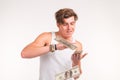 Rich, fun and finance concept - handsome young man throws money over white background.