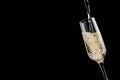 Rich golden flow of fizz champagne pour to wine glass on black background, closeup, detail, copy space. Festive luxury background.