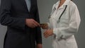 Rich male patient gives money to doctor, expensive health insurance, bribe