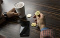 Rich man holding a bitcoin coin and drinking a coffee with a phone and gold coins of bitcoin on a table. Profit from