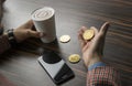 Rich man holding a bitcoin coin and drinking a coffee with a phone and gold coins of bitcoin on a table. Profit from