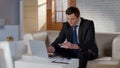 Rich man in suit paying with bank card using laptop, online money transaction Royalty Free Stock Photo