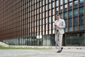 Busy middle aged business man using phone walking on city street, full body. Royalty Free Stock Photo