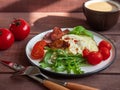 Rich omelet breakfast with grilled sausage and fresh tomatoes and a cup of coffee with milk, cutlery on a wooden tray, side view Royalty Free Stock Photo