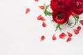 Rich red buttercup flowers in vase with petals top view on soft white wooden table. Elegance spring bouquet.