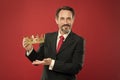 Rich reward. Mature businessman showing crown reward on red background. Successfil big boss awarding winner with