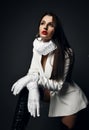 Rich sexy woman in white jacket, jabot frill, collar, gloves and high leather boots stands with her foot up, step on Royalty Free Stock Photo