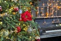 Richly decorated Christmas tree with red and gold ornaments and lights on the background of an old piano. Elegant card. closeup. Royalty Free Stock Photo