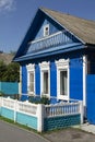 Richly decorated ornamental carved windows, frames on vintage blue wooden rural house. Countryside in Belarus