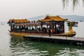 A richly decorated wooden cruise boat with tourists moored at a pier on the Kunming Lake Royalty Free Stock Photo