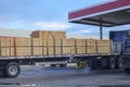 A fully loaded log truck at a diesel gas station pump