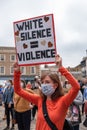A woman wearing a face mask holds an anti-racism banner above her head at a Black Lives Matter rally in Richmond, North Yorkshire