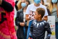 Young Superhero plays with action figures while protesters wear PPE Face Masks at a Black Lives Matter protest in Richmond, North