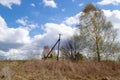 A rickety pole of a power line next to trees, against a background of cumulus clouds and blue sky. Royalty Free Stock Photo