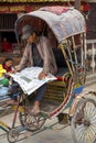 Rickshaw driver reading newspaper in Kathmandu