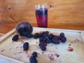 Blackberry caipirinha in a transparent glass cup, with some ripe blackberries on a wooden board on a wooden background. Royalty Free Stock Photo