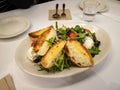 Ricotta cheese salad with arugula and other vegetables, olive, cherry tomato, and grilled garlic bread.