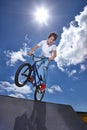 Ride, bike and teenager on ramp for sport performance, jump or training for event at park with blue sky mockup. Bicycle Royalty Free Stock Photo