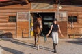 Rider in equestrian clothes holding the reins and leading horse from stables Royalty Free Stock Photo