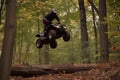 rider jumping atv over a forest log, leaves fluttering down Royalty Free Stock Photo