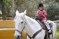 Rider little girl jockey hat white horse in park Royalty Free Stock Photo