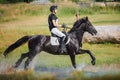 Rider man galloping fast in water pond on black stallion horse during eventing cross country competition Royalty Free Stock Photo