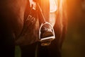 The rider`s foot, sitting in the saddle on a horse, is dressed in a black boot and rests on a metal stirrup. Equestrian sports. Royalty Free Stock Photo